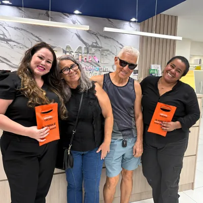 Quatro pessoas sorrindo juntas na recepção da clínica.