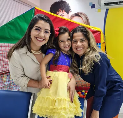 Duas mulheres com uma menina vestida de Branca de Neve junto à área infantil da clínica.